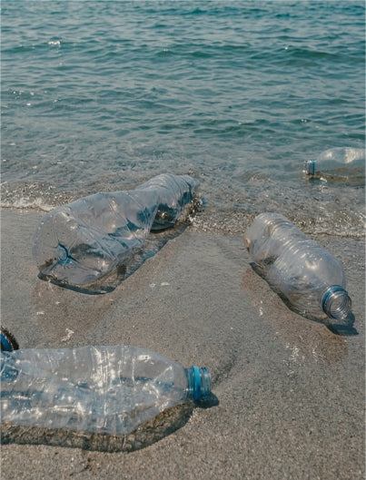 Plastic bottles on a beach with ocean water in the background
