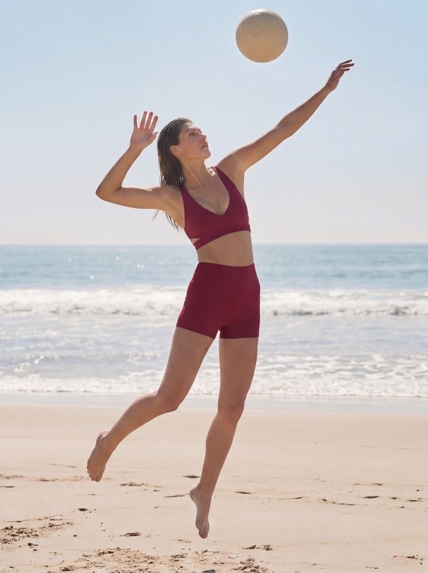Woman playing volleyball on a beach with ocean in the background