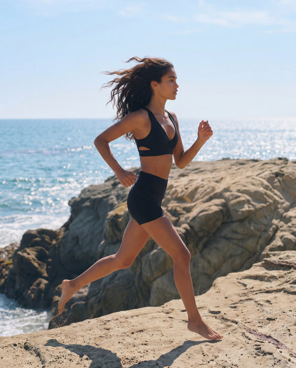 Woman running on a rocky beach with ocean in the background